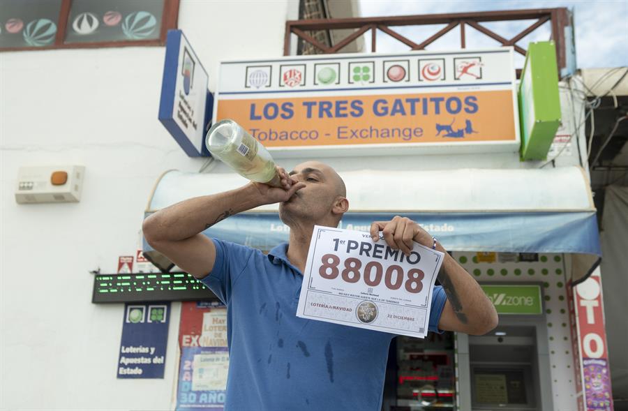El premio gordo de la Lotería de Navidad ha repartido 51 décimos en Canarias, con un total de 20.400.000 euros. En la imagen, el dueño de la Administración "Los Tres Gatitos" de Puerto del Carmen, Jonathan Torres, con el cartel del número premiado, el 88.008, del que ha repartido 9 décimos. EFE/ Adriel Perdomo