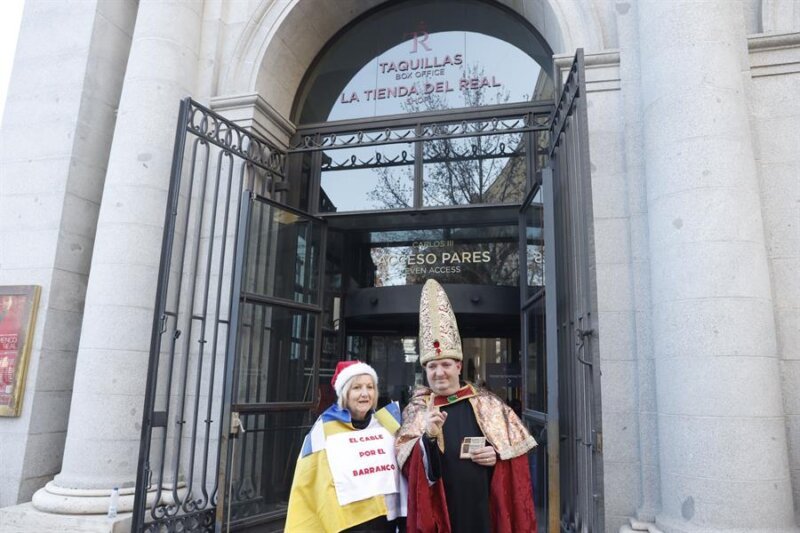 Un hombre disfrazado muestra sus décimos del número 0000 mientras espera en las puertas del Palacio Real para asistir al Sorteo Extraordinario de la Lotería de Navidad que se celebra mañana viernes. EFE/ Aitor Martin