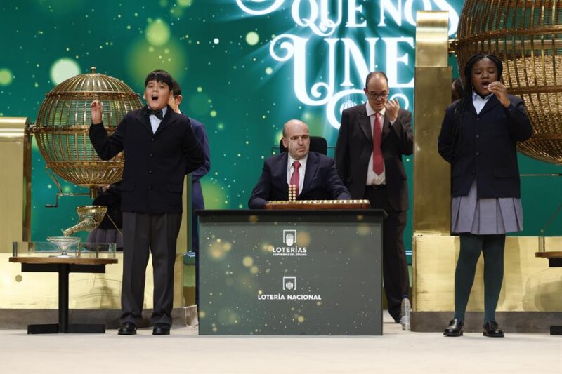 Yesica Paola Valencia Gómez y Francisco Moreno Durán cantan el gordo que este año ha recaído en el número 88.008 durante el sorteo extraordinario de Navidad de la Lotería Nacional este viernes en el Teatro Real de Madrid. EFE/ J.J. Guillén