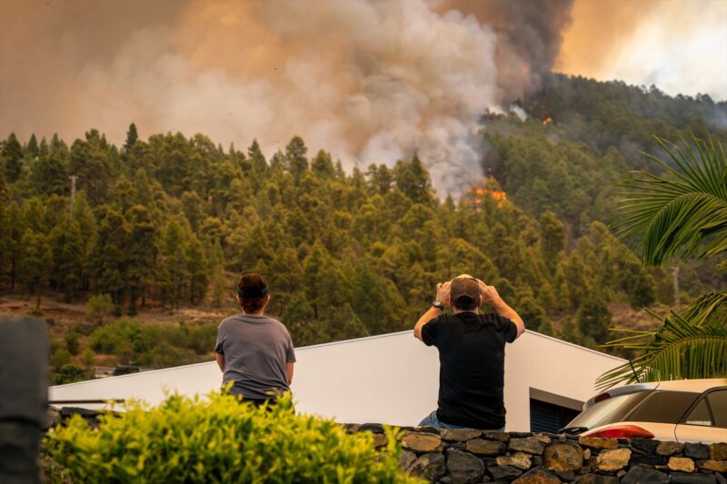 Dos vecinos observan las llamas del incendio forestal declarado en la Palma, a 15 de julio de 2023, en Puntagorda, La Palma. Imagen Europa Press