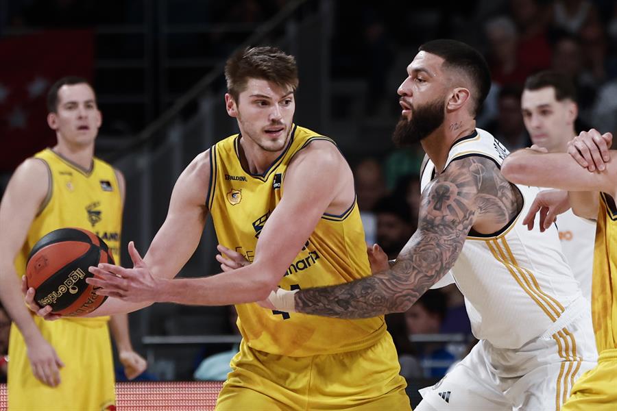 El pivot estadounidense del Gran Canaria, Ben Lammers (i), con el balón ante el jugador francés del Real Madrid, Vicent Poirier. Imagen EFE