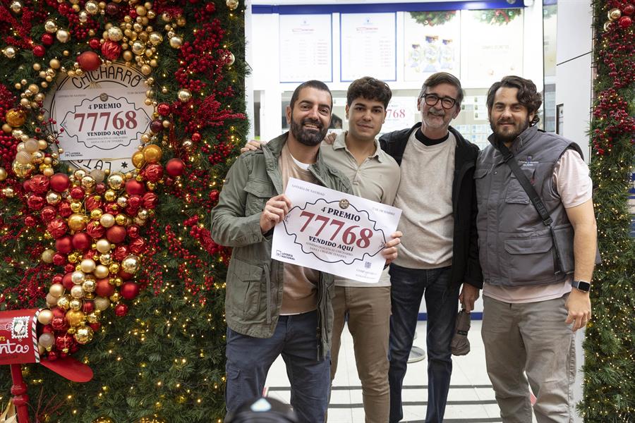 El dueño de la administración número 16 de Santa Cruz de Tenerife, Javier Hernández Cebrián (i), posa con el cartel del número 77768, uno de los cuartos premios del sorteo extraordinario de Navidad de la Lotería Nacional, vendido en su establecimiento. EFE/ Miguel Barreto