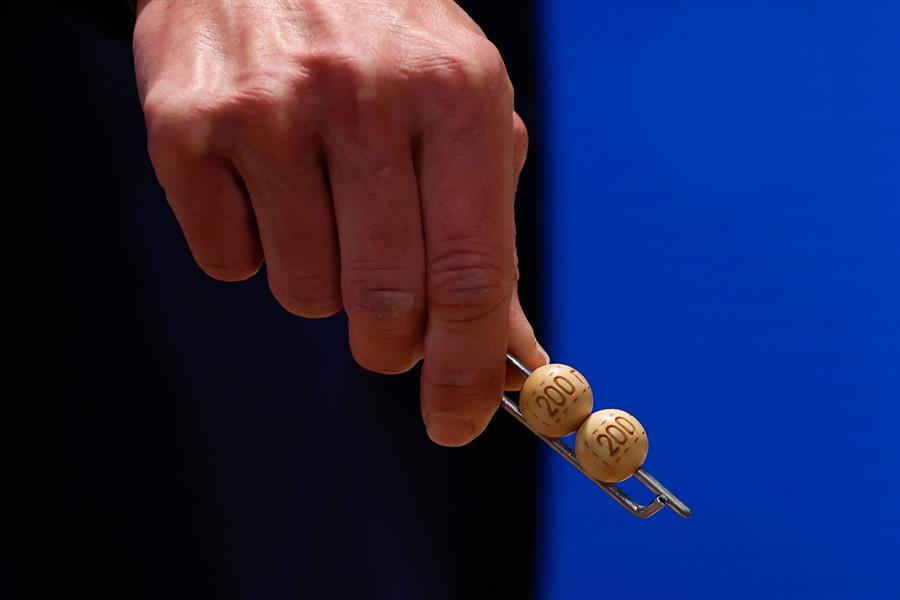 Un responsable enseña las bolas de los dos cuartos, de 200.000 euros, antes de ser introducidas en su respectivo bombo durante preparativos para el sorteo de la Lotería de Navidad este domingo en el Teatro Real, en Madrid. EFE/Javier Lizón