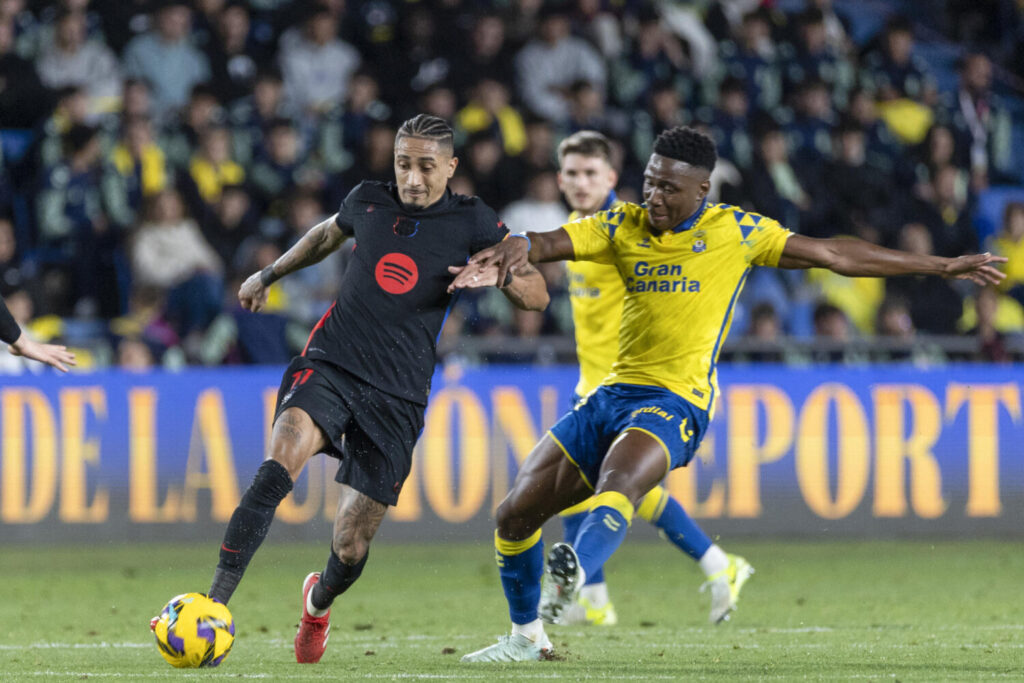 0 – 2 UD Las Palmas – FC Barcelona | J25 LaLiga EA Sports. LAS PALMAS DE GRAN CANARIA, 22/02/2025.- El delantero brasileño del FC Barcelona Raphinha (i), pelea un balón con el centrocampista portugués de la UD Las Palmas, Dario Essugo, durante el encuentro correspondiente a la jornada 25 de Laliga EA Sports que disputan hoy sábado en el estadio de Gran Canaria. EFE / Quique Curbelo
