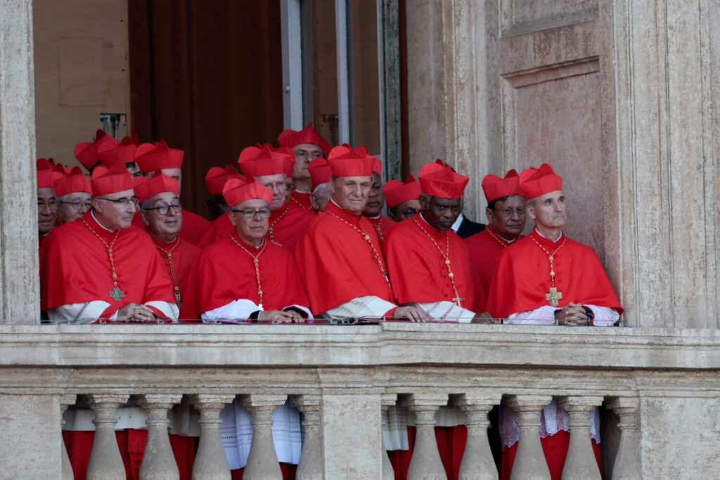 Cardenales escuchan desde un balcón mientras el recién elegido Papa León XIV, Cardenal Robert Prevost de los Estados Unidos pronuncia el mensaje «Urbi et Orbi» (a la ciudad y al mundo) desde el balcón de la Basílica de San Pedro, en el Vaticano, 8 de mayo de 2025. REUTERS/Remo Casilli