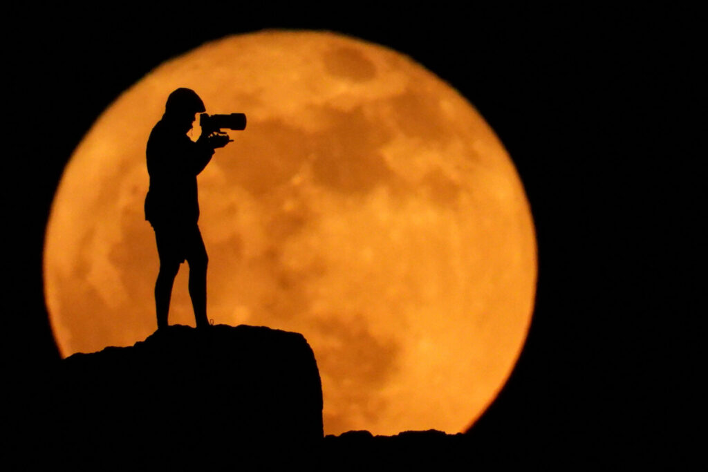 Un fotógrafo se siluetea contra la luna llena conocida como luna de fresa en Arinaga, Gran Canaria, 11 de junio de 2025. REUTERS/Borja Suárez