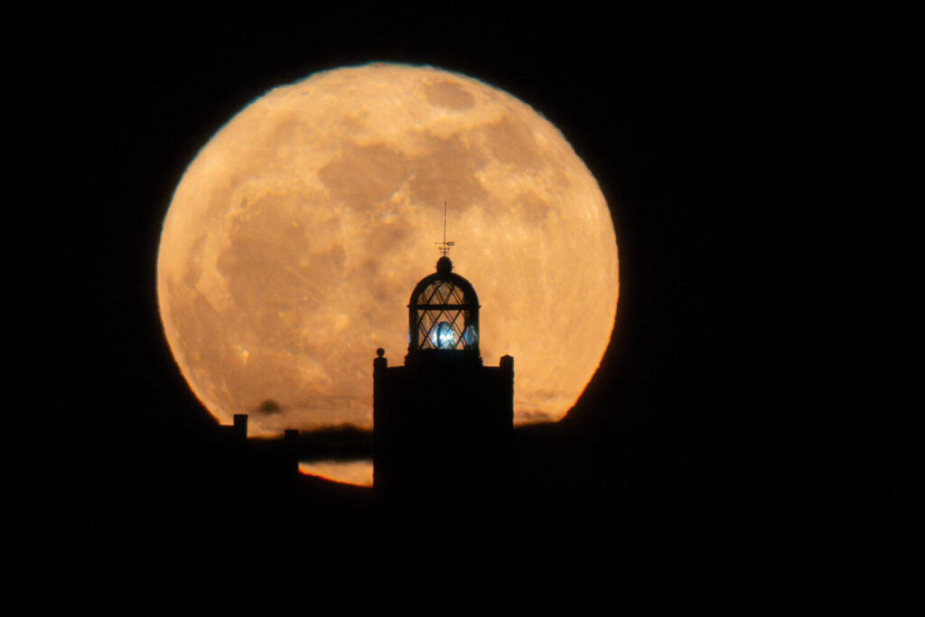 TUINEJE (FUERTEVENTURA), 12/06/2025.- La luna de fresa esta noche junto al Faro de la Entallada. Esta primera luna llena de junio coincide con un fenómeno astronómico poco común, el lunasticio, fenómeno por el cual el astro alcanza la inclinación más extrema dentro de su órbita, y no se volverá a repetir hasta el año 2043. EFE/Carlos de Saá