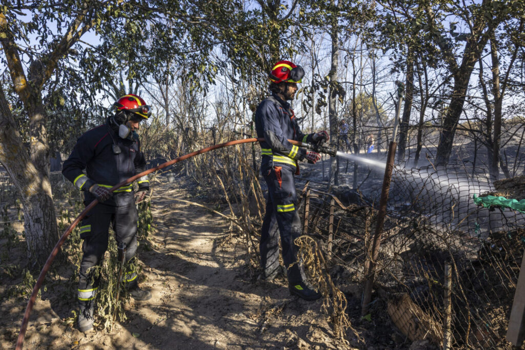 Los bomberos trabajan el campo quemado en la localidad toledana de Méntrida este viernes, que atraviesa horas de "calma tensa" a la espera de ver cómo evoluciona el incendio forestal declarado este jueves y que afecta a la provincia de Toledo y a la Comunidad de Madrid, que se encuentra ya perimetrado al 95 %