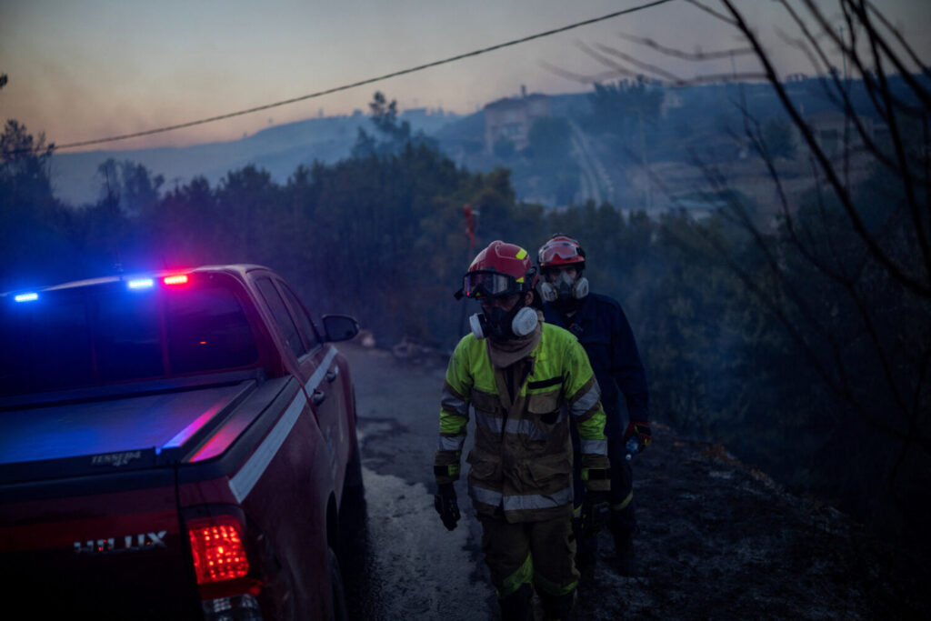 Los bomberos caminan por una zona quemada mientras un incendio forestal arde en el pueblo de Kryoneri, cerca de Atenas, Grecia, el 26 de julio de 2025. REUTERS/Alkis Konstantinidis