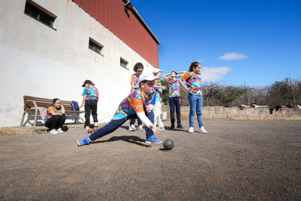 Niños y niñas participan en una jornada de bola canaria dentro de los Juegos Cabildo, fomentando el deporte tradicional y los valores del juego en equipo.