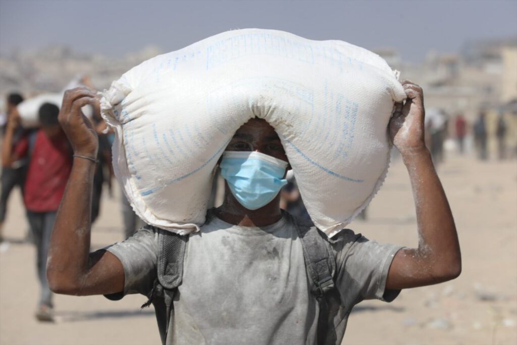 Un palestino con un paquete de harina entregada por un camión de ayuda humanitaria en el norte de la Franja de Gaza