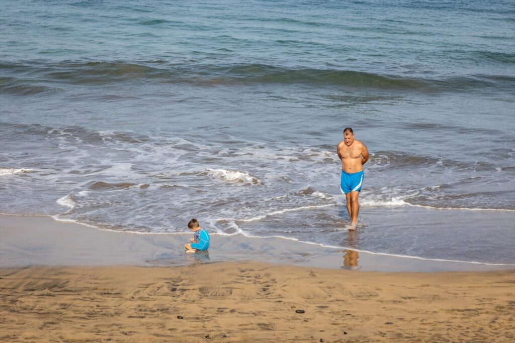 Imagen de archivo de un bañista y un niño en la playa.