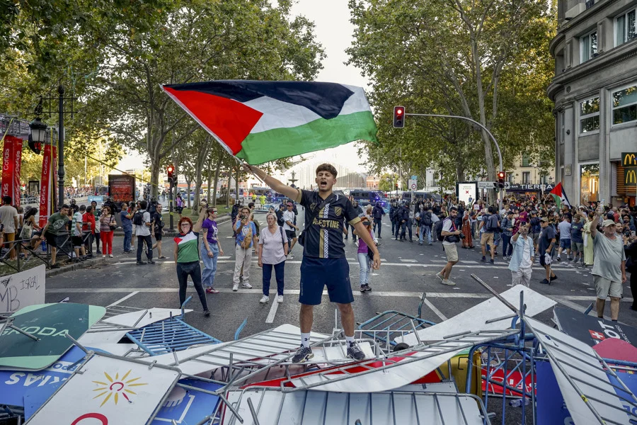 Manifestantes propalestinos cortan el recorrido de los ciclistas en el Paseo del Prado, este domingo, durante la última etapa de la Vuelta a España que se disputa entre las localidades madrileñas de Alalpardo y Madrid, con un recorrido 103,6 Km.- EFE/ Daniel González