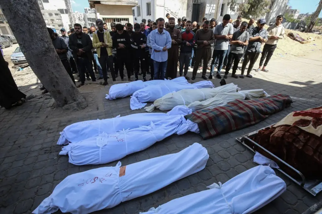 Palestinos rezan junto a los cadáveres de varias personas asesinadas por el Ejército de Israel en Gaza