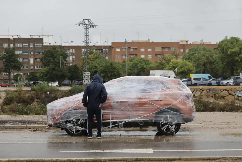Un hombre observa un coche protegido para la lluvia este jueves en Catarroja (Valencia). El Centro de Coordinación de Emergencias de la Generalitat ha emitido un aviso especial ante la llegada de la dana Alice, con lluvias intensas y tormentas, que podrían dar lugar a inundaciones locales repentinas en zonas bajas, arroyos y ramblas, y que ha obligado a suspender los actos del Día de la Comunitat Valenciana