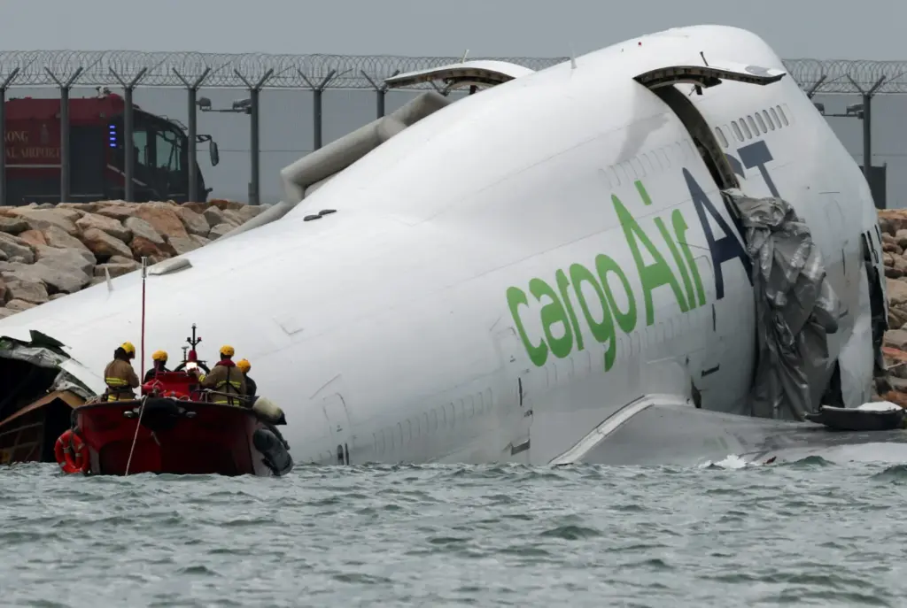 Personal de emergencia trabaja cerca de un avión de carga que se encuentra parcialmente en el mar después de que se desvió de la pista durante el aterrizaje en el Aeropuerto Internacional de Hong Kong en Hong Kong, China, el 20 de octubre de 2025. REUTERS/Tyrone Siu