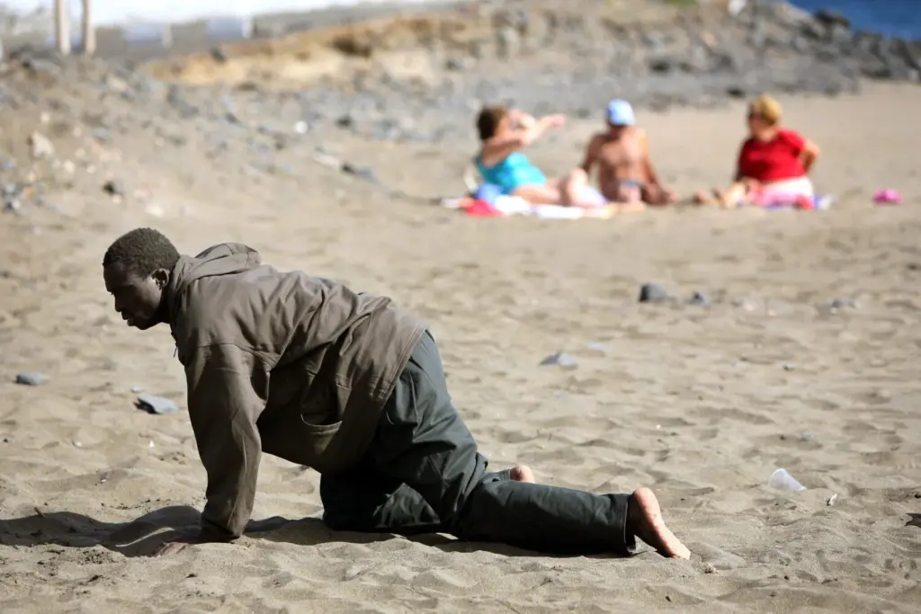Una persona se arrastra tras su llegada en una patera a la playa de Gran Tarajal, en Fuerteventura, en las Islas Canarias, España, el 5 de mayo de 2006. REUTERS/Juan Medina.