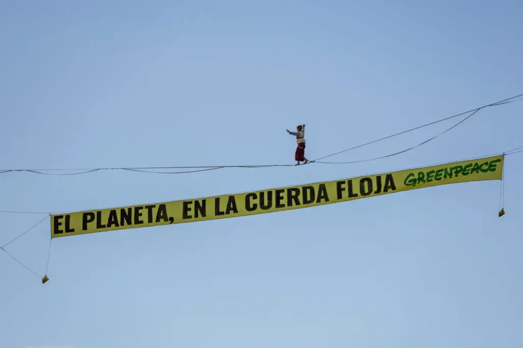 Una activista de Greenpeace camina por una cuerda floja sobre el centro de Madrid para exigir fin de los combustibles fósiles