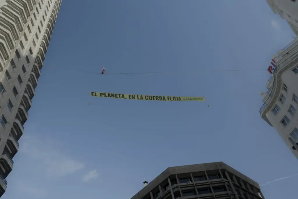 Una activista de Greenpeace camina por una cuerda floja sobre el centro de Madrid para exigir fin de los combustibles fósiles