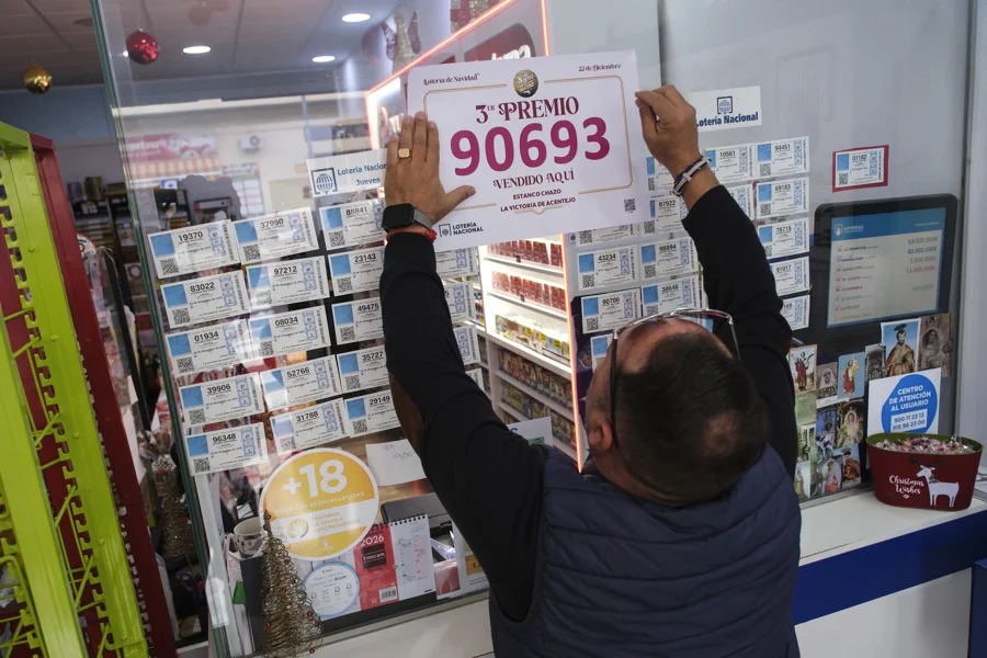 LA VICTORIA DE ACENTEJO (TENERIFE) (ESPAÑA), 22/12/2025.- Un funcionario de la lotería coloca este lunes un cartel que anuncia que el estaco El Chazo, situado en el municipio tinerfeño de La Victoria de Acentejo, ha sido uno de los puntos de venta del tercer premio de la lotería de navidad. EFE/Alberto Valdés