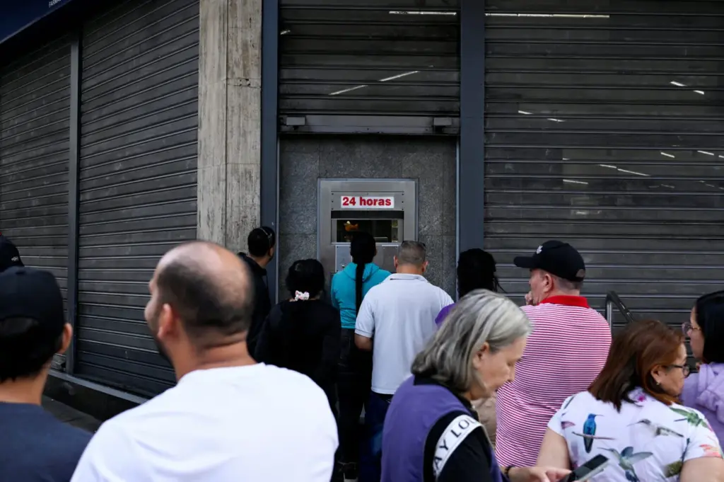 La gente hace fila frente a la ventanilla de una farmacia, abierta las 24 horas, después de que el presidente estadounidense, Donald Trump, dijera que Estados Unidos había atacado a Venezuela y capturado a su presidente, Nicolás Maduro, en Caracas, Venezuela, el 3 de enero de 2026. REUTERS/Maxwell Briceno