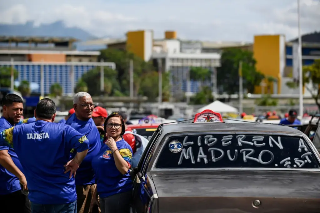 Trabajadores del transporte venezolanos se reúnen junto a un automóvil pintado con la leyenda "Libertad para Maduro" antes de una caravana en apoyo al presidente Nicolás Maduro y su esposa Cilia Flores, más de una semana después de que Estados Unidos lanzara un ataque contra el país, en Caracas, Venezuela, el 13 de enero de 2026. REUTERS/Maxwell Briceno