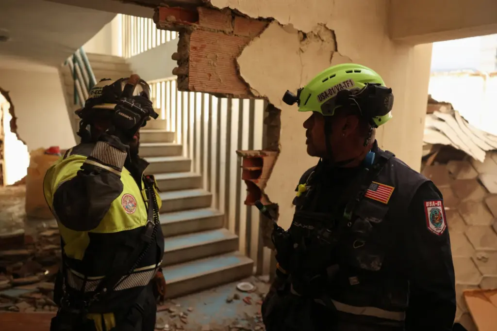 Un miembro del Cuerpo de Bomberos ECU-11 de Guayaquil, Ecuador, y un miembro de un equipo de rescate estadounidense participan en las labores de rescate en un edificio que se derrumbó desde la planta baja hasta el quinto piso, tras fuertes terremotos, en La Guaira, Venezuela, el 29 de junio de 2026. REUTERS/Leonardo Fernández Viloria
