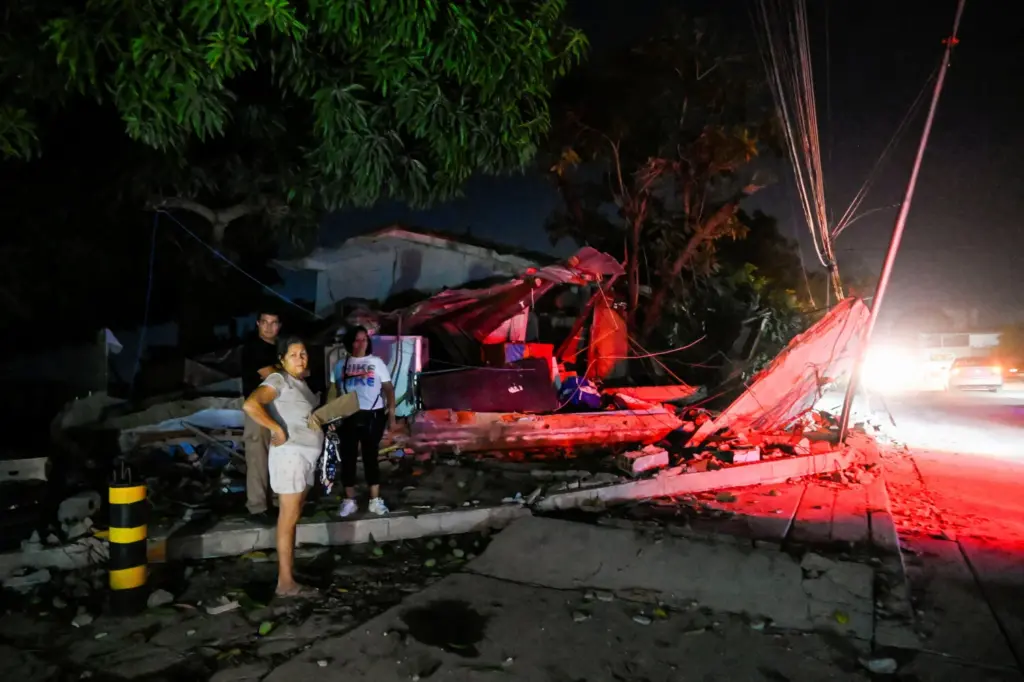 People stand next to a destroyed building after earthquakes, in La Guaira, Venezuela, June 25, 2026. REUTERS/Maxwell Briceno