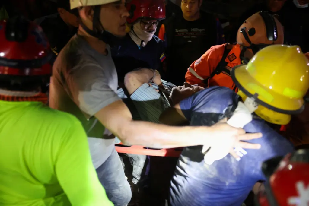 Equipos de rescate trasladan a una víctima en una camilla mientras los servicios de emergencia trabajan en el lugar de un edificio colapsado tras los terremotos que afectaron al país, en Caracas, Venezuela, el 25 de junio de 2026. REUTERS/Leonardo Fernandez Viloria
