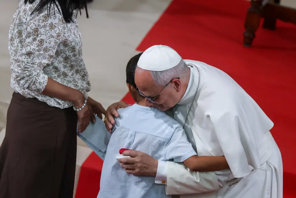 El papa León XIV abraza a un niño durante un encuentro con organizaciones benéficas diocesanas en la iglesia de Sant Agustí