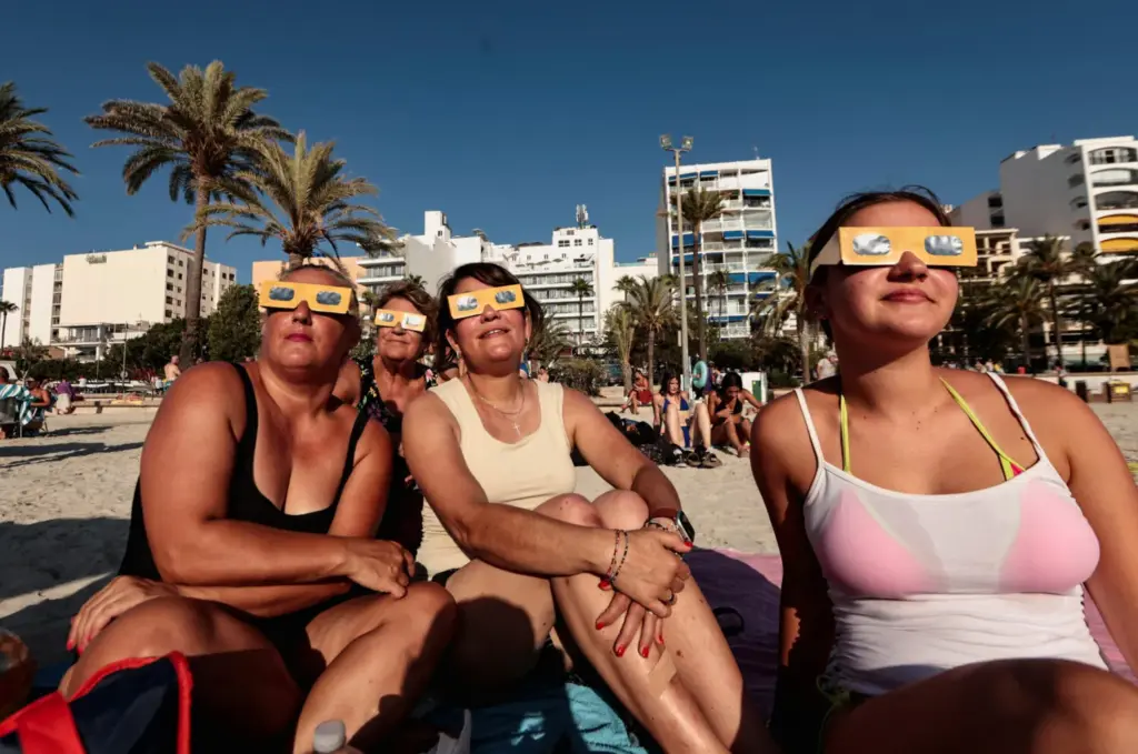 Personas de Colonia, Alemania, prueban sus gafas protectoras antes de un eclipse solar, en la playa de El Arenal en Mallorca, España, el 12 de agosto de 2026