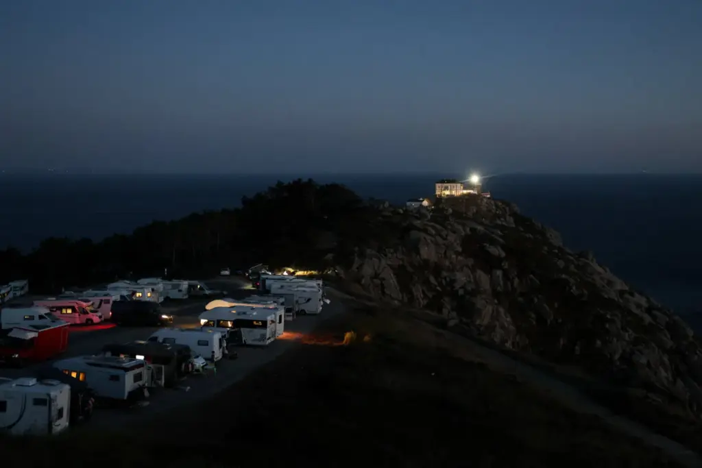 Turistas en autocaravanas y autocaravanas esperan solar un eclipse solar frente al faro de Cape Fisterra el día antes del eclipse solar, en la Costa da Morte. Imagen Reuters