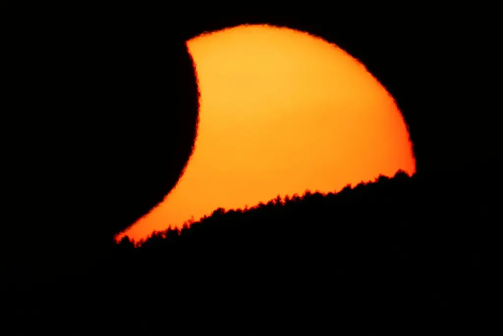 La luna cubre parcialmente el sol al atardecer, tras un eclipse solar total, visto desde Arija, España, el 12 de agosto de 2026