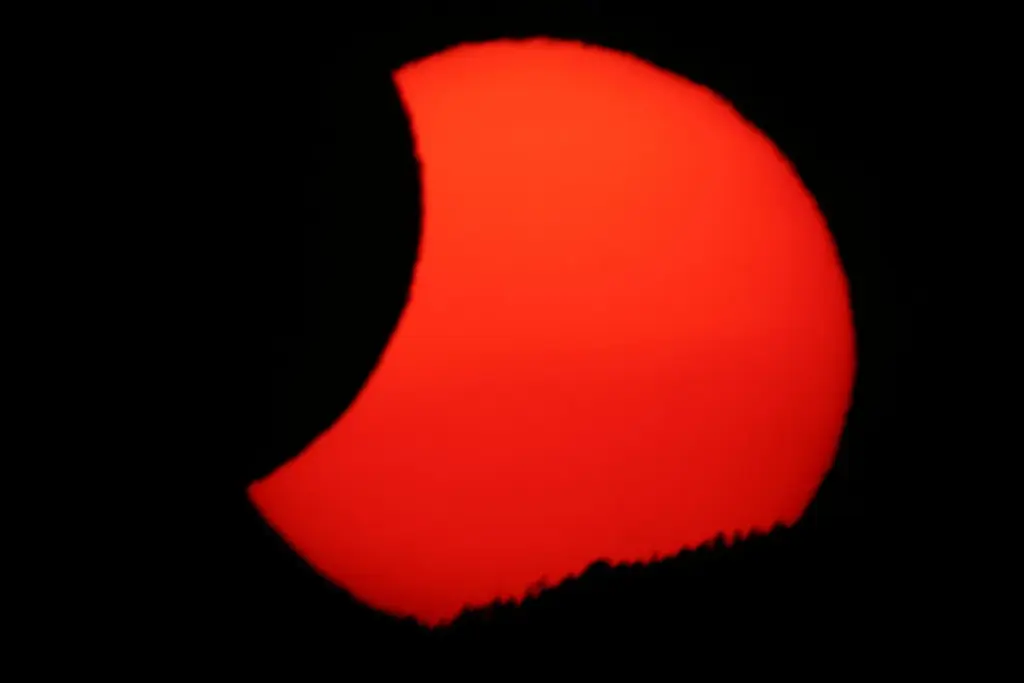 La luna cubre parcialmente el sol al atardecer, tras un eclipse solar total, visto desde Arija, España, el 12 de agosto de 2026
