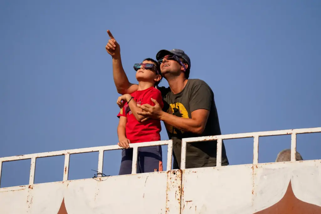 Un hombre y un niño prueban sus gafas protectoras ante un eclipse solar en una plaza de toros de Villalba del Rey, España, el 12 de agosto de 2026