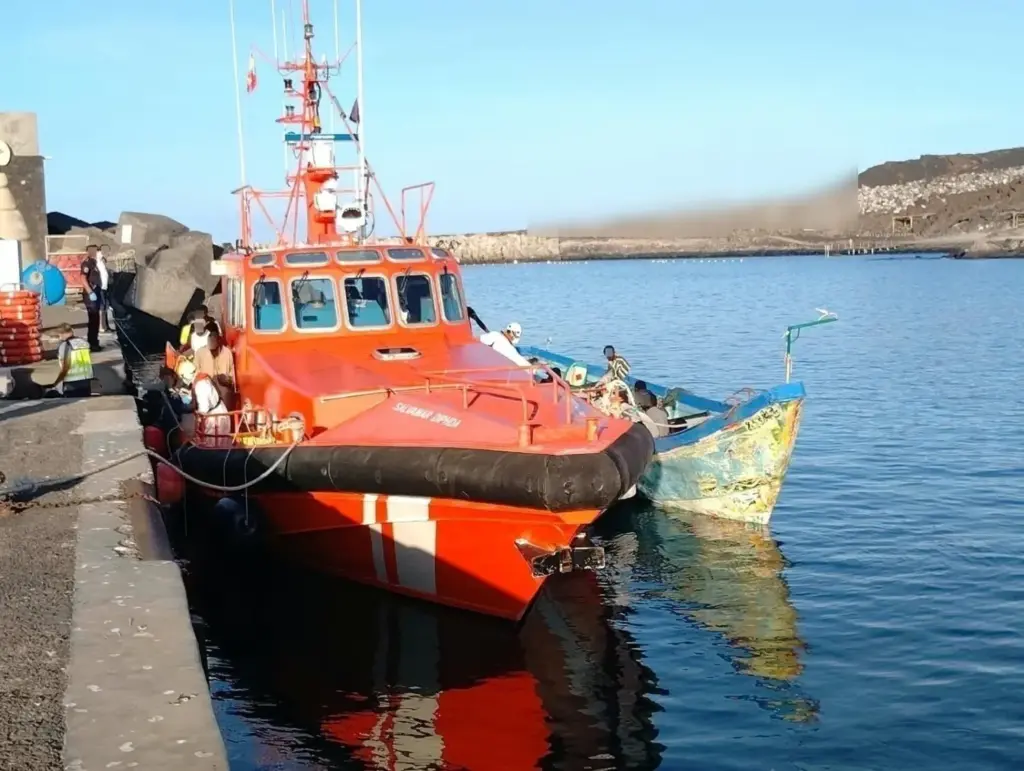 Un cayuco junto a una embarcación de Salvamento Marítimo en el puerto de La Restinga REMITIDA / HANDOUT por SALVAMENTO MARÍTIMO