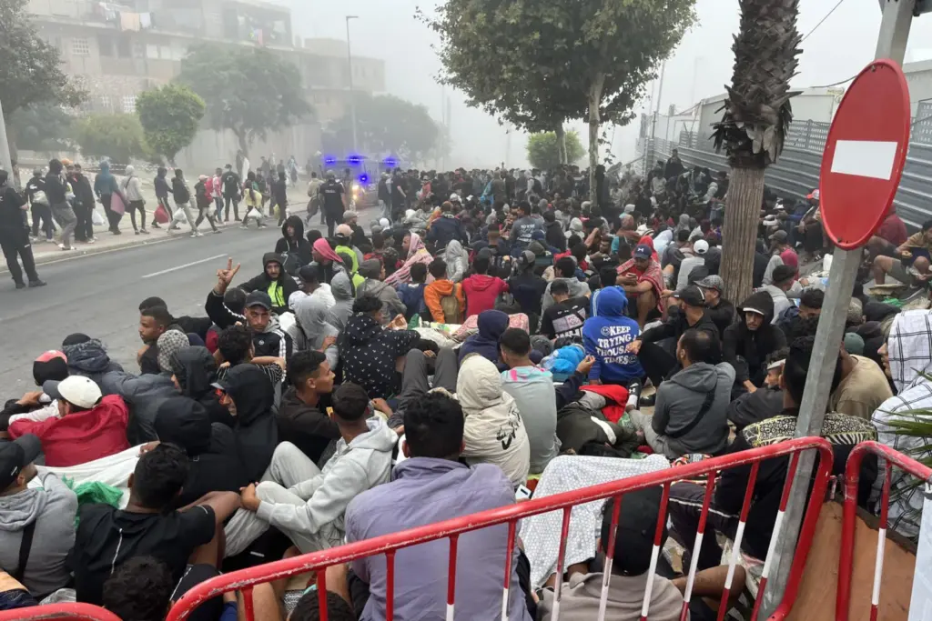 Migrantes siguen concentrados en las inmediaciones de la explanada de embolsamiento de Loma Colmenar de Ceuta este miércoles con la esperanza de conseguir una plaza en un nuevo centro de acogida. EFE/Reduan