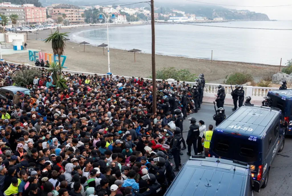 Playa Benítez, Ceuta, cientos de migrantes sentados ante un despliegue policial. Imagen EFE