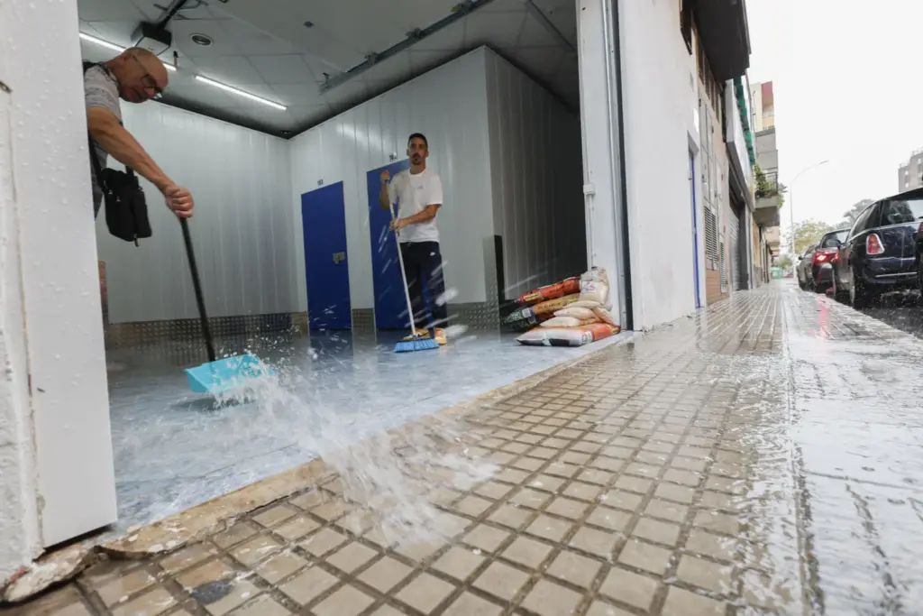 GANDIA (VALENCIA), 18/10/2026.- Vecinos retiran agua de unos trasteros tras las fuertes lluvias este domingo en Gandía.