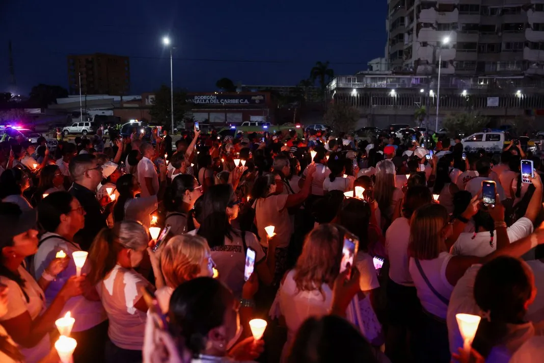Personas que sostienen velas encendidas aguardan a que un haz de luz ilumine el cielo durante una vigilia y oración denominada "Haz de Luz", con motivo de los 100 días transcurridos desde los dos terremotos que afectaron a Venezuela. REUTERS/Leonardo Fernandez Viloria